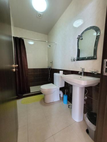 une salle de bain avec un lavabo, des toilettes et un miroir dans l'établissement Apartments Sunset Paradise, à Makhinjauri