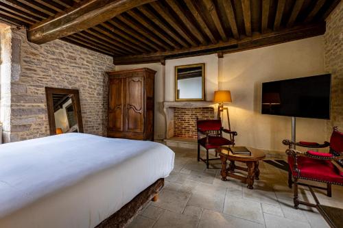 um quarto com uma cama, uma televisão e cadeiras em Les Remparts Hôtels et Demeures Historiques em Beaune