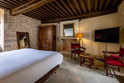 - une chambre avec un lit, une télévision et des chaises dans l'établissement Les Remparts Hôtels et Demeures Historiques, à Beaune