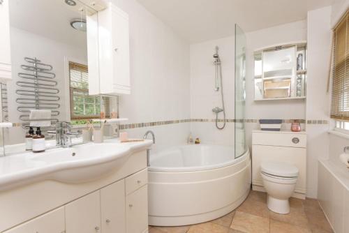 a white bathroom with a tub and a toilet and a sink at Pump Cottage and Annexe, Gwithian in Gwithian