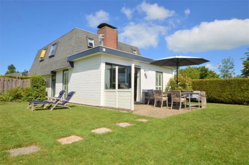 a house with a table and chairs and an umbrella at Kustverhuur, Park Schoneveld, Zeester 38 in Breskens