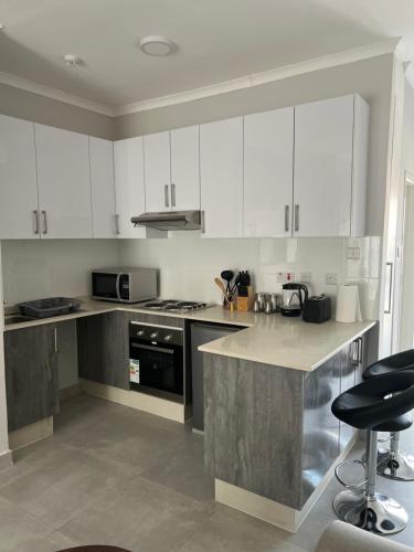 a kitchen with white cabinets and a stove top oven at Sarona City L203 in Gaborone