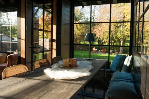 een grote afgeschermde veranda met een houten tafel en stoelen bij GITE AU BORD DE L'AISNE in Érezée