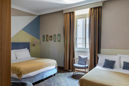 a hotel room with two beds and a chair at Boutique Hotel Galatea in Rome