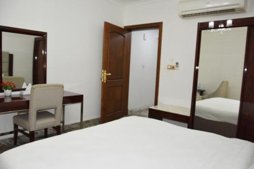 a hotel room with a bed and a desk and a bedroom at Royal Suite Hotel Apartments in Al Ḩuwayl