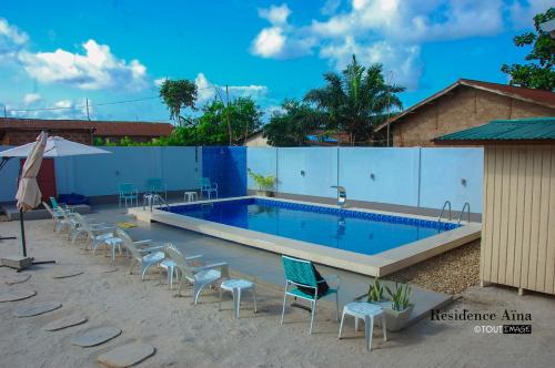 a large swimming pool with chairs around it at RESIDENCE AINA in Abomey-Calavi