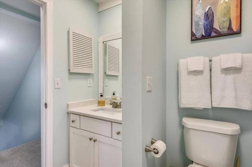 een badkamer met een toilet, een wastafel en een spiegel bij Cozy 2BR 1,5BA Condo at Gulf Highlands - 5 Min Walk to Beach! With 11 Pools! in Panama City Beach