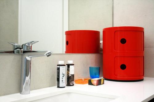 un bancone del bagno con lavandino e contenitori rossi di Splash Suites with Private Pools a Nikiana