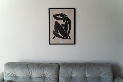 a couch against a white wall with a picture of a lizard at Apartamenty Przystanek Morska in Gdynia