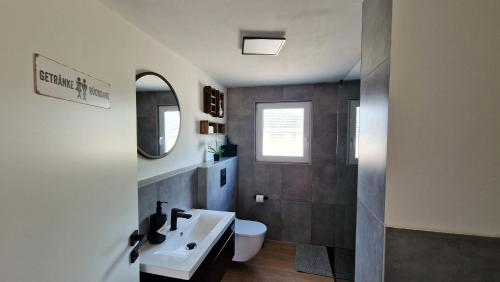 a bathroom with a sink and a toilet and a mirror at Ferienhaus Seeoase - 70qm - Kamin -Terrassen - Parkplatz - Badestelle fußläufig in Joachimsthal