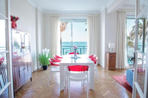 une salle à manger avec une table blanche et des chaises rouges dans l'établissement Bel Appartement Face à La Mer Près Du Centre - Le Voilier by Halldis, à Cannes