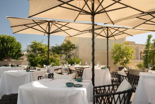 a restaurant with white tables and umbrellas at Patria Palace Lecce - The Leading Hotels of The World in Lecce