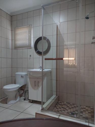 a bathroom with a toilet and a glass shower at Pro Plants Accommodation in Kimberley