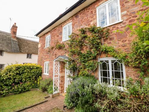 an old brick house with white windows and plants at Vine Cottage in Minehead