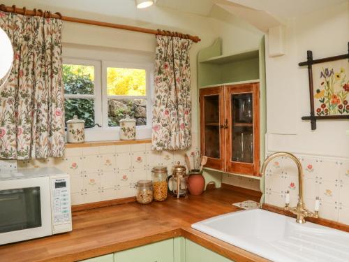a kitchen with a sink and a microwave at Vine Cottage in Minehead