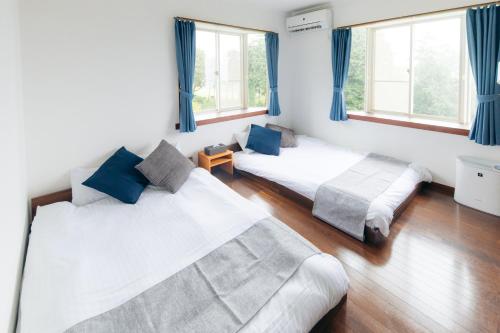 two beds in a room with blue curtains at chillout house 大室山 in Ito