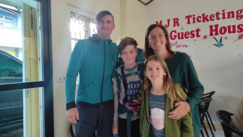 a family posing for a picture in front of a guest house at MJR Ticketing Guest House in Ruteng