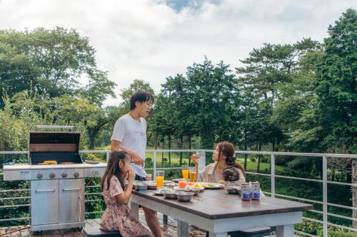 a man and two girls sitting at a picnic table with a man at chillout house 大室山 in Ito