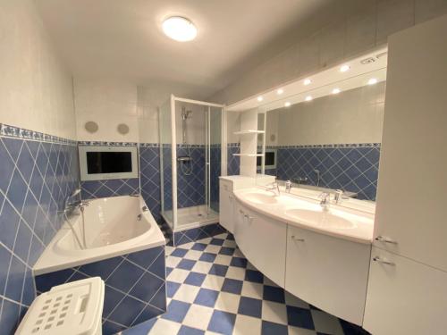 a blue and white bathroom with two sinks and a tub at Callantsoger Staete A109 in Callantsoog