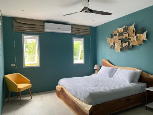 a blue bedroom with a bed and a ceiling fan at Le Petit Saint Tropez in Khanom
