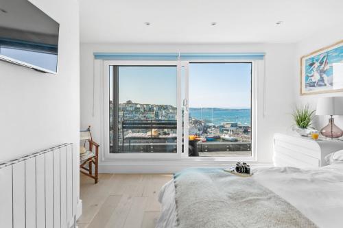 a white bedroom with a large window with a view at The Captain's Cottage, Brixham in Brixham