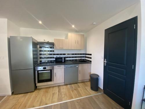 a kitchen with stainless steel appliances and a black door at Appartement confortable et paisible in Loupiac-de-Cadillac