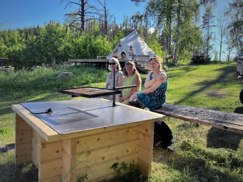 a group of three women standing next to a wooden table at Bakgården i Revsund in Gällö