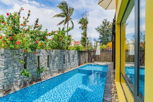 a swimming pool next to a stone wall with a swimming pool at May Villa 6BR Beachfront An Bang Beach Hoi An by Beachside Boutique Homes in An Bàn (2)
