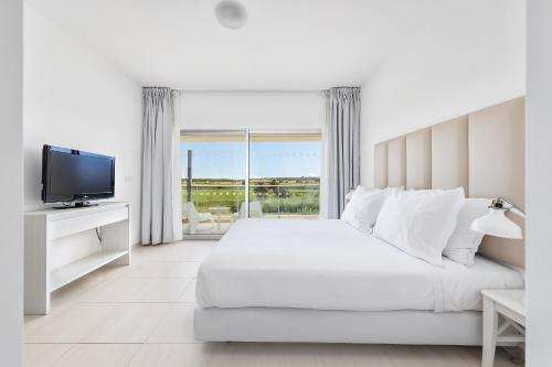 a white bedroom with a large bed and a television at Laguna - Vilamoura in Vilamoura