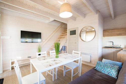 a white dining room with a white table and chairs at Łódź Wikingów in Rowy