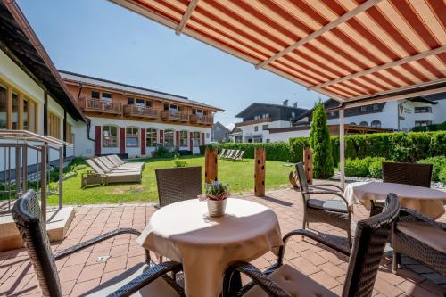 a patio with two tables and chairs under a pergola at Hotel Zum Gourmet in Seefeld in Tirol