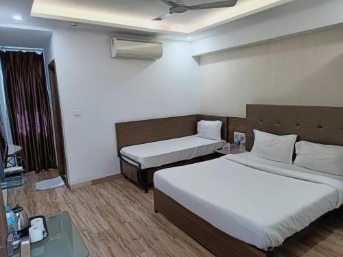 a hotel room with two beds and a tv at Alba Premier, Indore in Indore