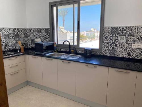 a kitchen with white cabinets and a window and a sink at La casa blanca in Houmt Souk