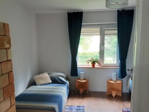 um pequeno quarto com uma cama e uma janela em Dom na Suwalszczyźnie em Krasnopol