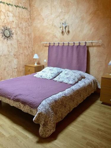 Gîte Le Roucoul في Maraussan: غرفة نوم مع سرير مع لحاف أرجواني