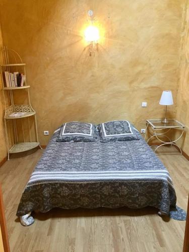 a bedroom with a bed with a blue comforter at Gîte Le Roucoul in Maraussan