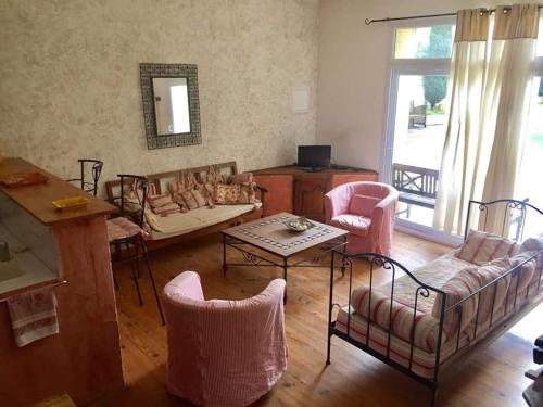 Gîte Le Roucoul في Maraussan: غرفة معيشة مع كراسي وأريكة وطاولة