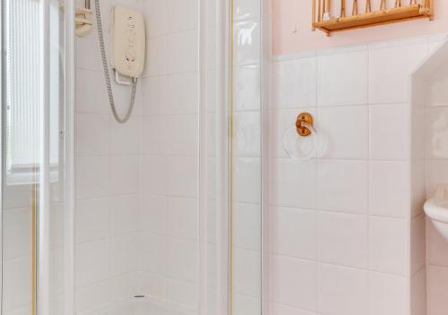 a shower with a glass door in a bathroom at Cookies Coastguard Cottage in New Romney