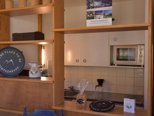 une cuisine avec un comptoir avec une horloge et un four micro-ondes dans l'établissement Appartement cosy 2 pièces au pied des pistes, parking et casier à skis - FR-1-266-62, à Montgenèvre