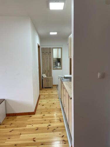 a kitchen with white walls and a wooden floor at Apartments Gorska in Kolašin