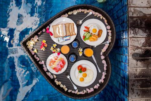 a tray of breakfast food on a table next to a pool at The Sun Hotel & Spa Legian in Legian