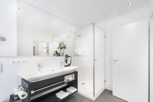 y baño blanco con lavabo y ducha. en HerzogsPark Apartments mit oder ohne Küche, en Herzogenaurach