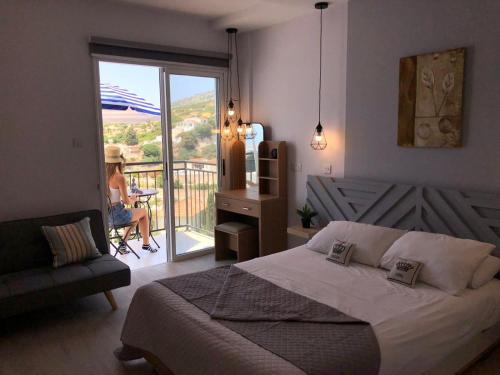 ein Schlafzimmer mit einem Bett und eine Frau auf einem Balkon in der Unterkunft Panoramic Holidays - Superior 38 in Peyia