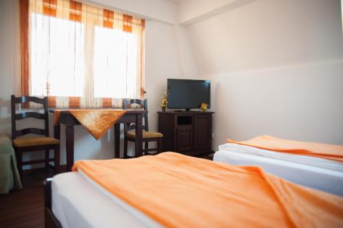 a room with two beds and a table and a television at Pensiunea Acasa in Sibiu