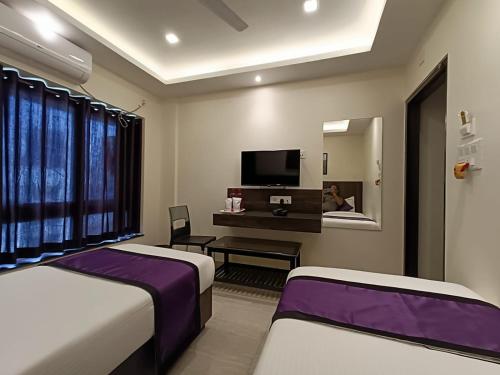 a hotel room with two beds and a tv at Sheldon Inn Kolkata in Kolkata