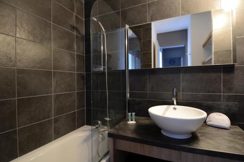 a bathroom with a sink and a tub and a mirror at Résidence Odalys Le Hameau du Mottaret in Méribel