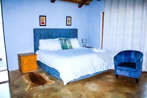 a blue bedroom with a bed and a blue chair at Harnham Mountain Lodge in Louis Trichardt