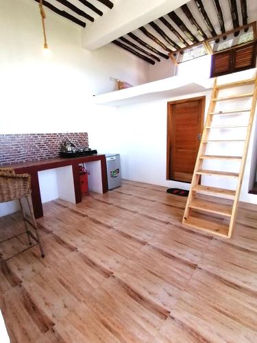 Camera con pavimento in legno e scala. di New Arisen Bungalows a Bwejuu