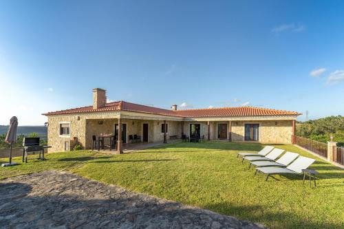 a house with a group of benches in the yard at Villa Junceira - refúgio de luxo perto do Castelo in Óbidos