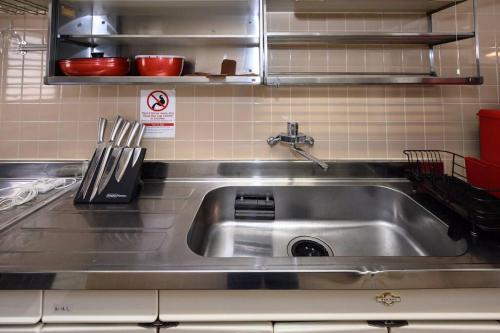 a stainless steel sink in a kitchen with utensils at G’Day Senbayashi in Osaka